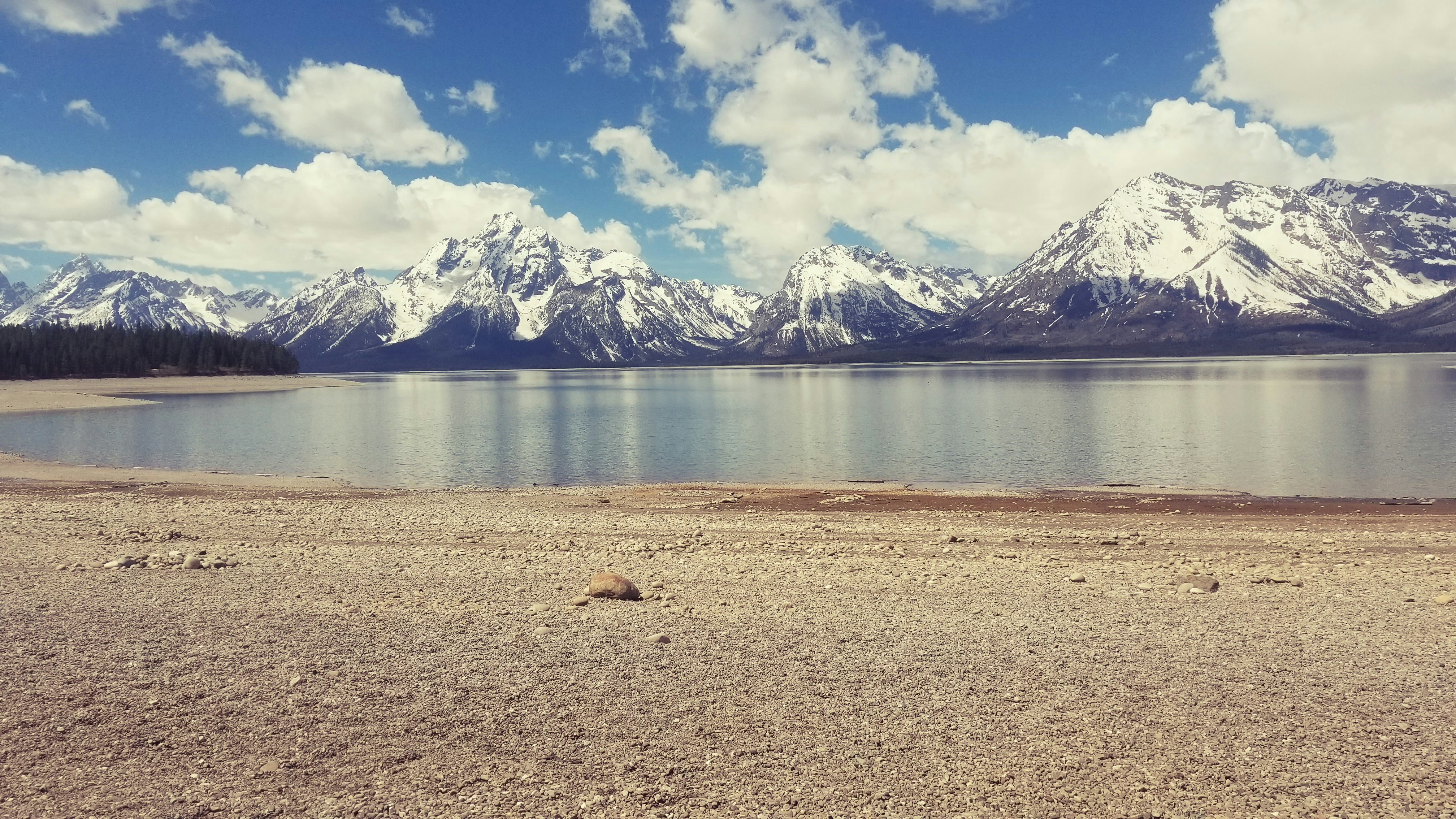 a lake surrounded by snow covered mountains under a blue sky