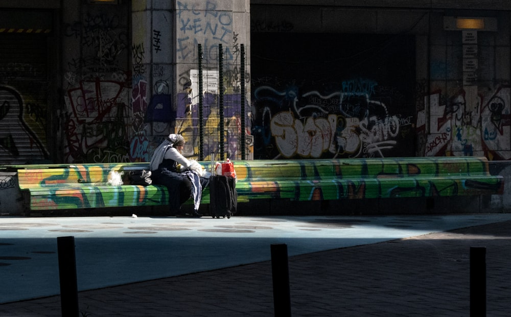 a man sitting on a bench covered in graffiti