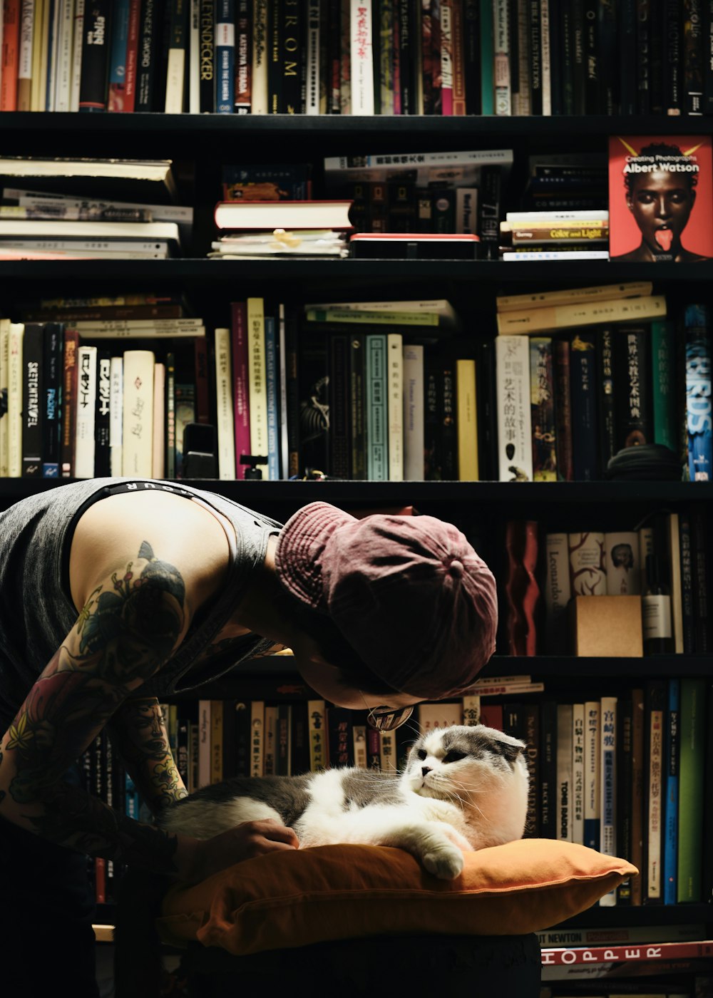 a person with a cat in front of a bookshelf