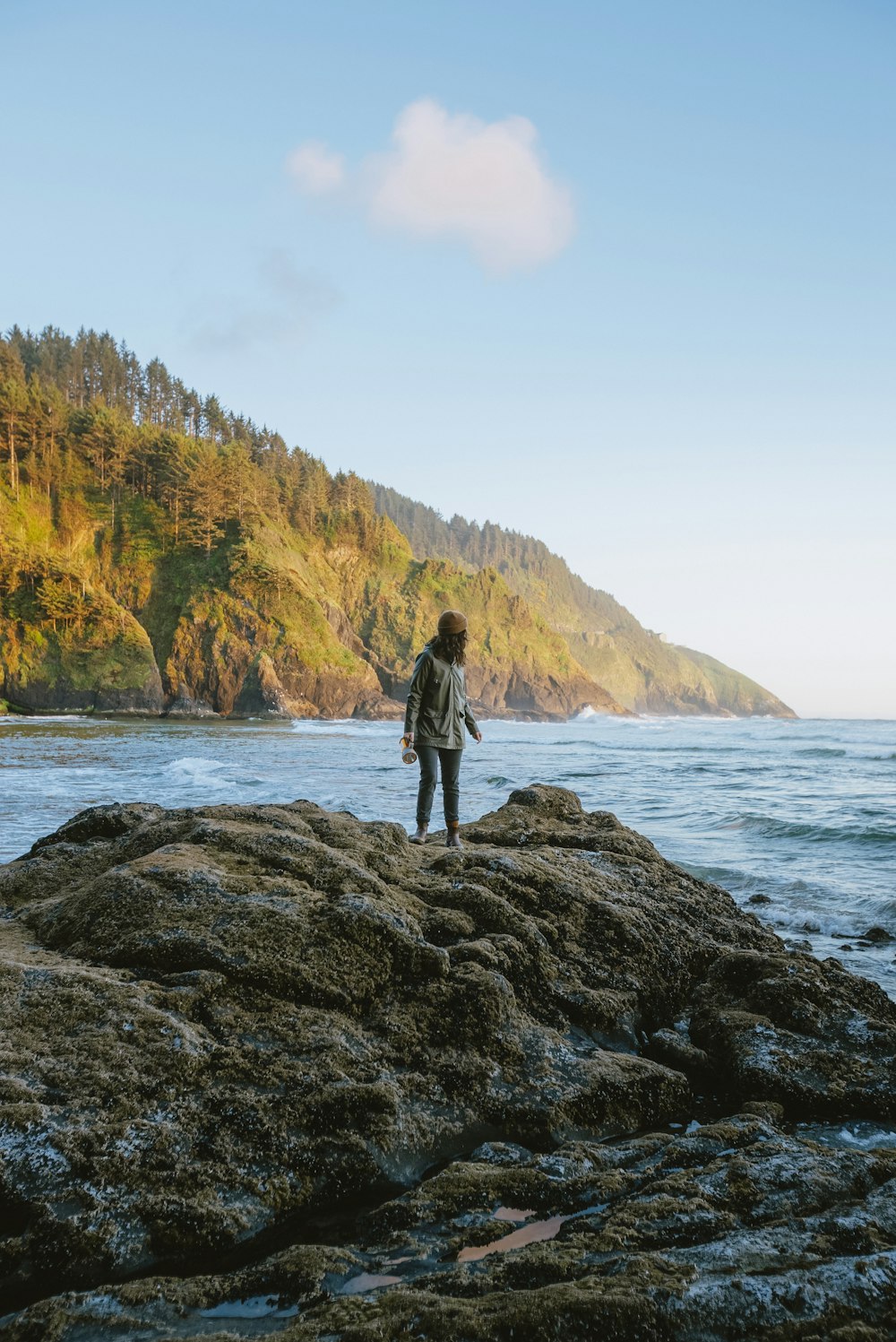 a man standing on top of a rocky beach next to the ocean