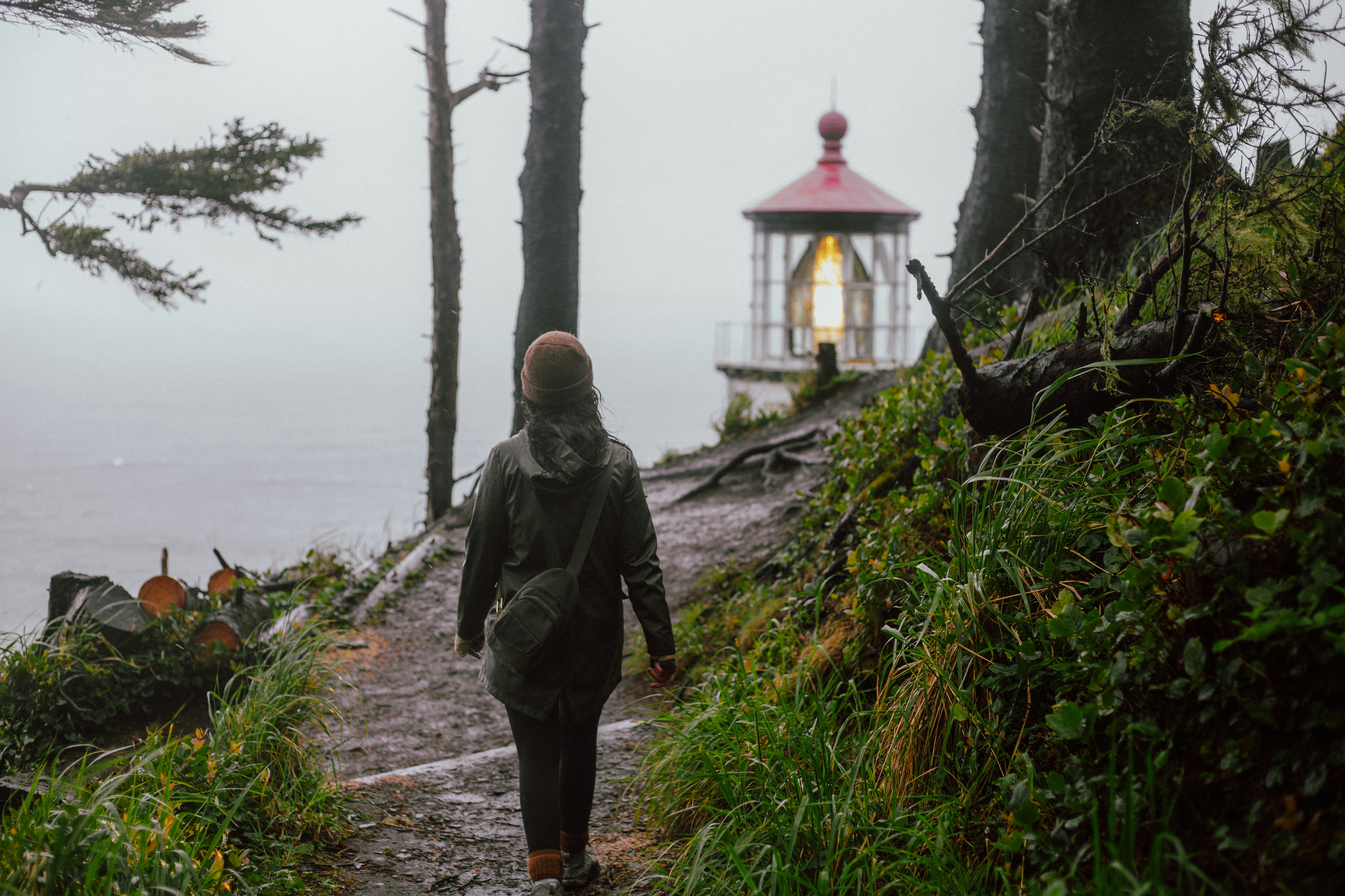 a person walking down a path towards a light house, 
