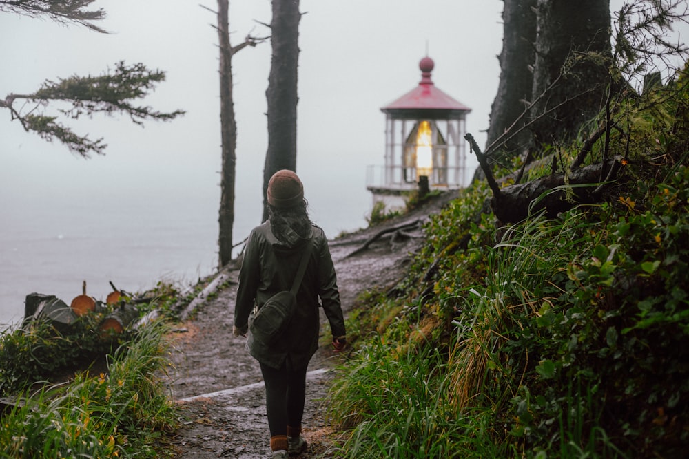 a person walking down a path towards a light house