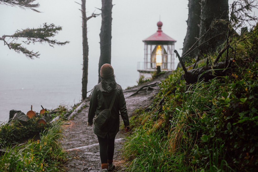 a person walking down a path towards a light house,