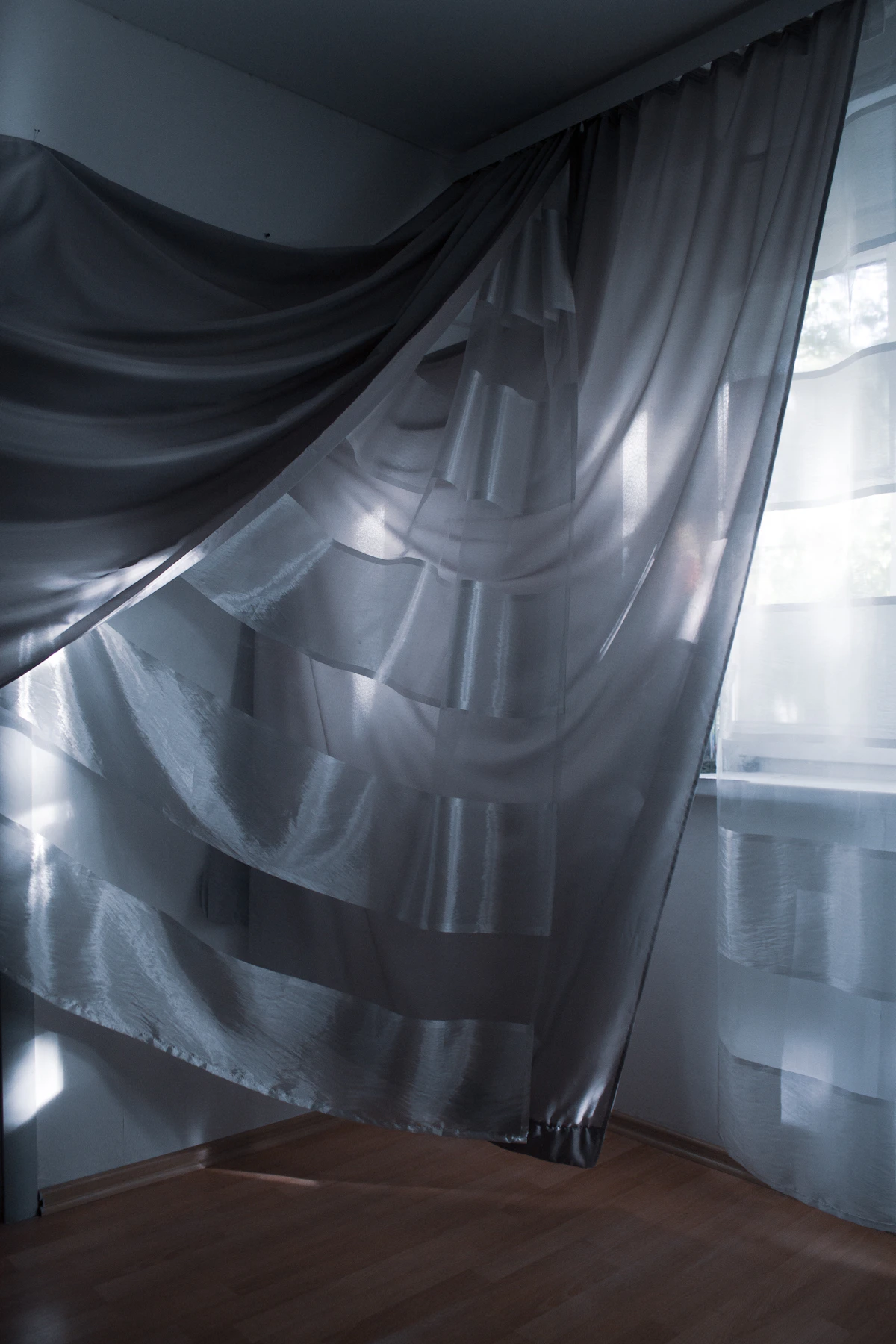 Sheer curtains hanging at a window, filtering daylight