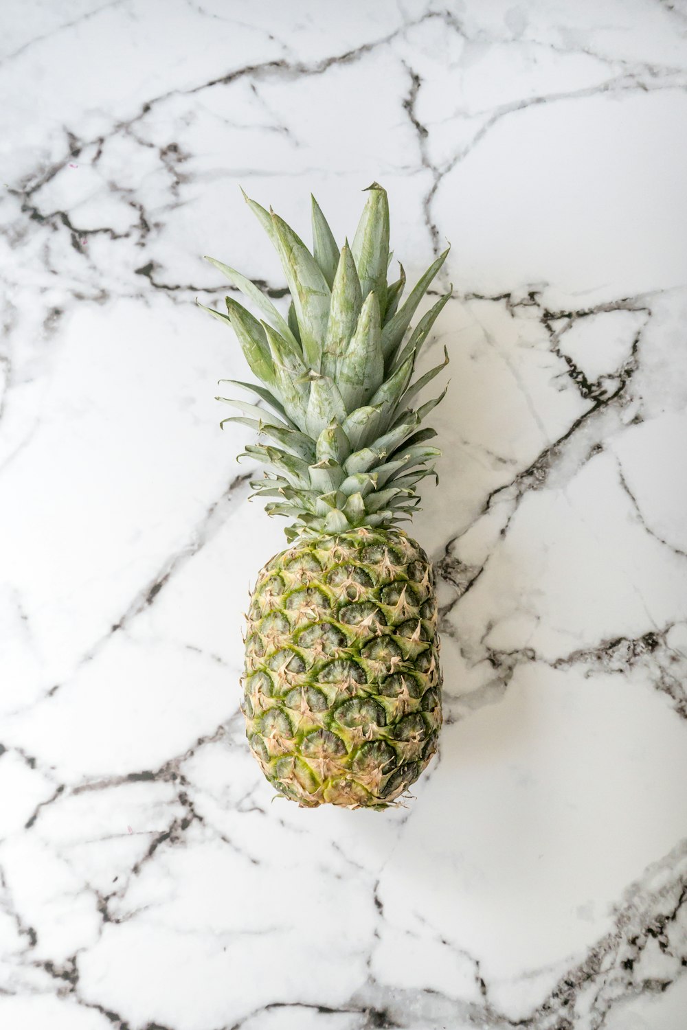 a pineapple sitting on a marble counter top