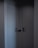 Two minimalist, modern doors with sleek black handles set in a dark corner, casting subtle shadows. The walls and doors have a smooth, matte finish, contributing to a clean, contemporary look.