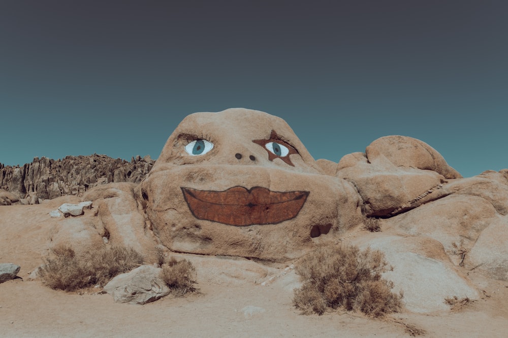 uma escultura de areia de um rosto sorridente no deserto