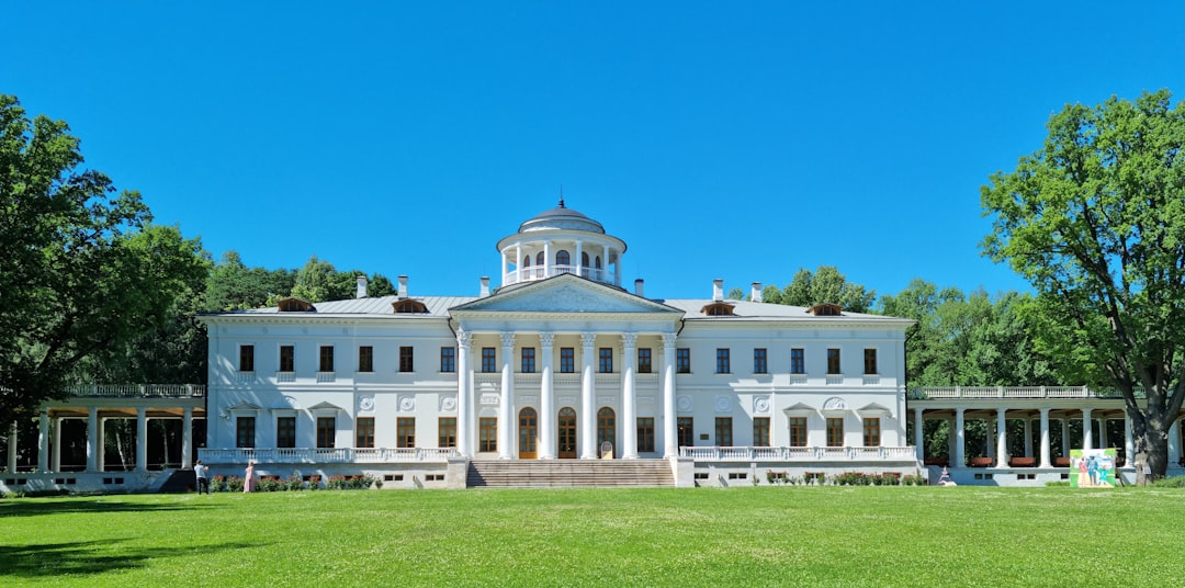 a large white building sitting on top of a lush green field, The main building of the Ostafyevo mansion