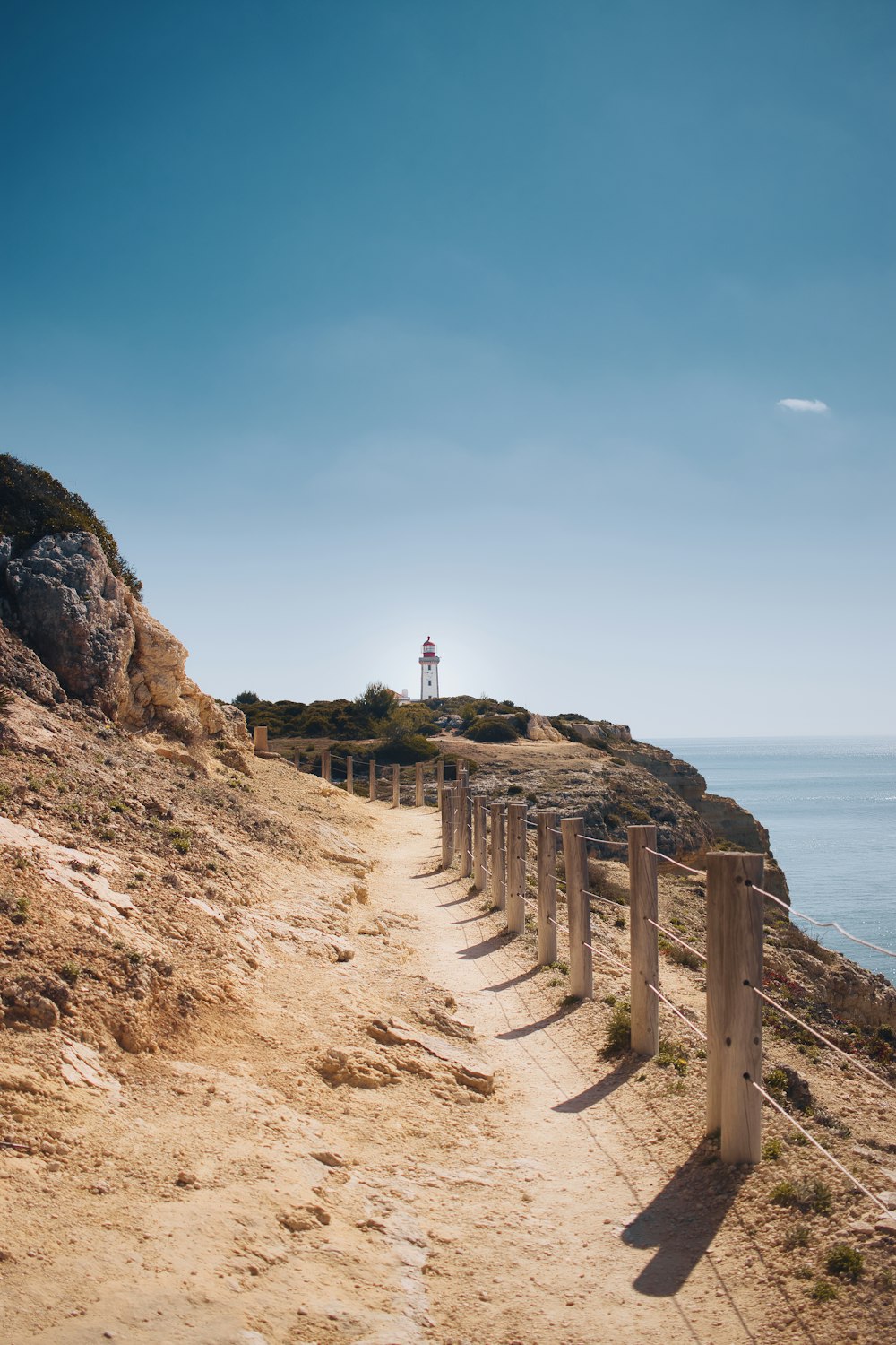 un chemin menant à un phare sur une falaise