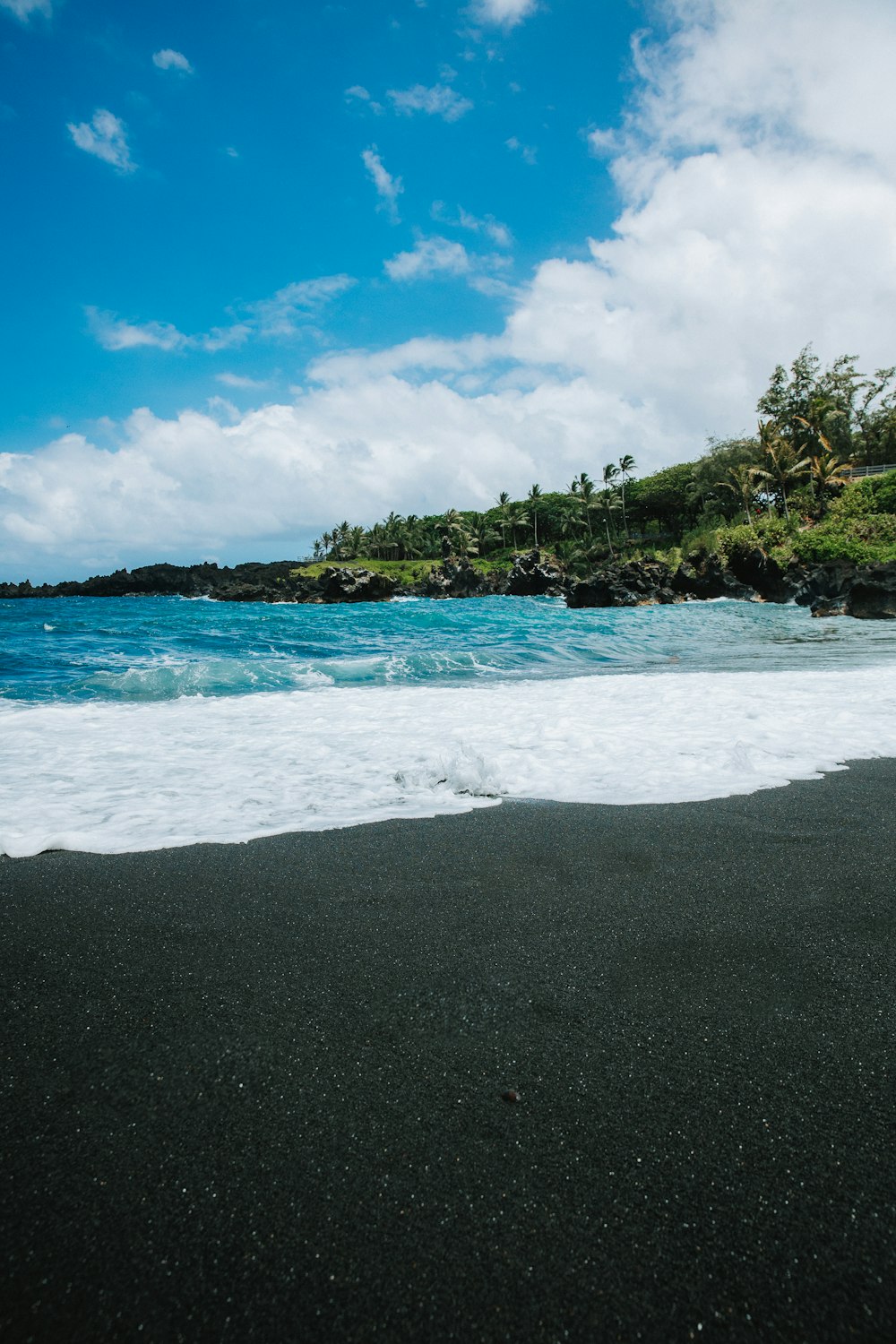 a black sand beach with waves coming in to shore