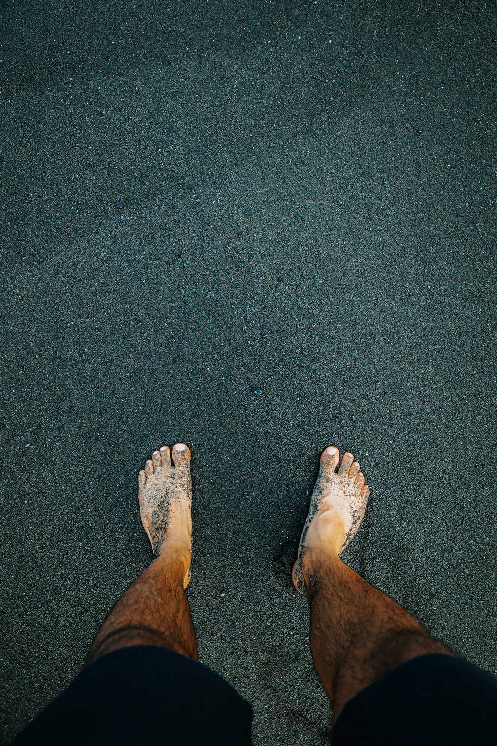 a person standing in the sand with their feet in the sand