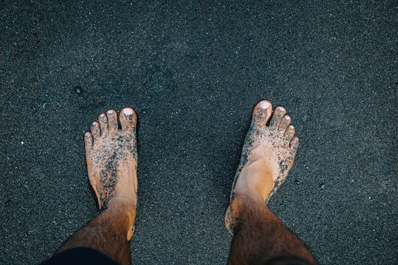 a person standing in the sand with their feet in the sand