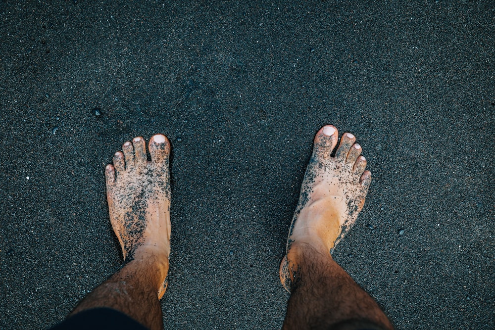 a person standing in the sand with their feet in the sand