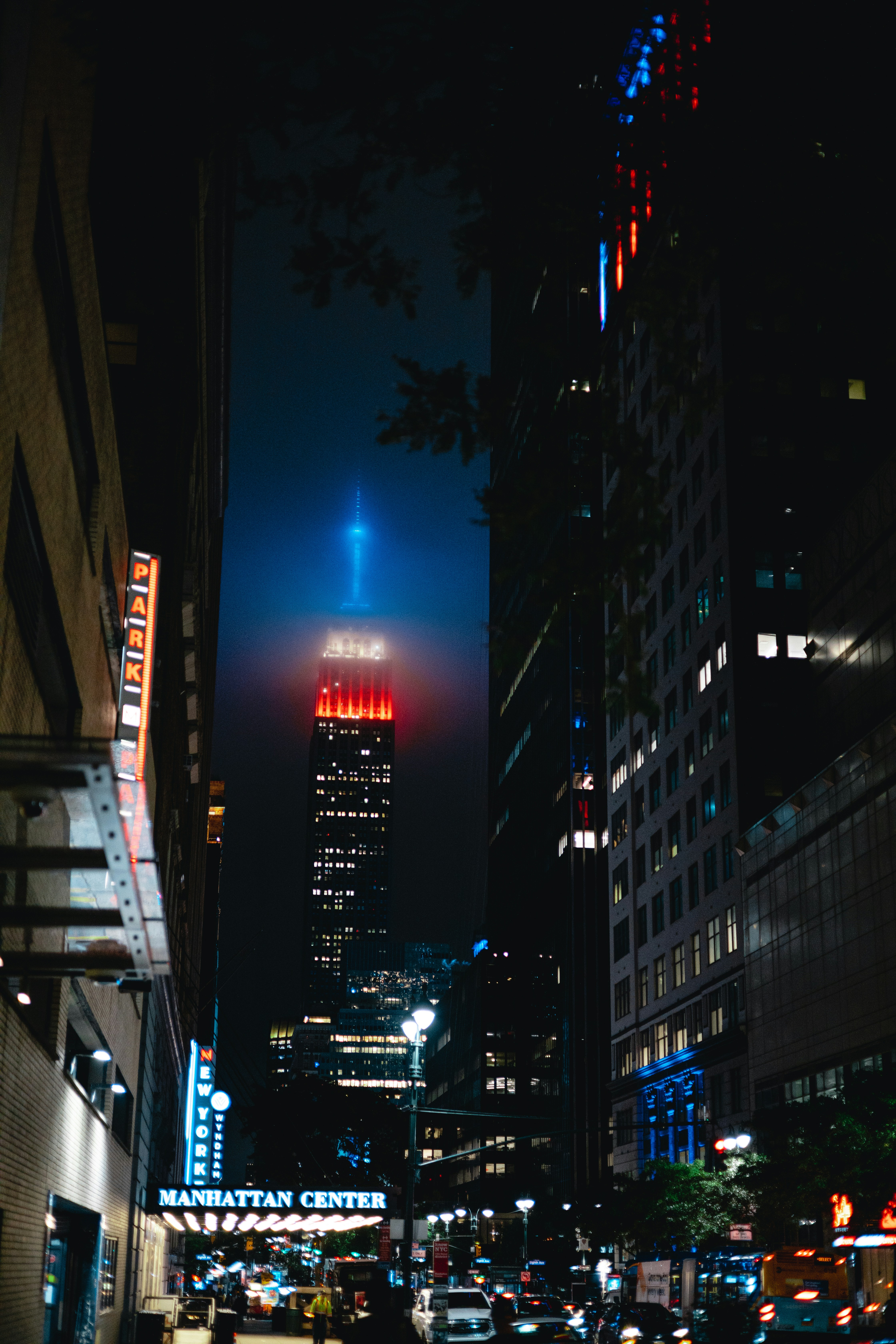a city street at night with a tall building in the background