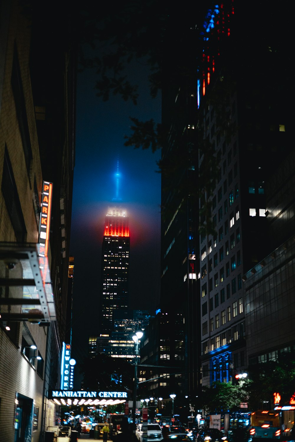 a city street at night with a tall building in the background