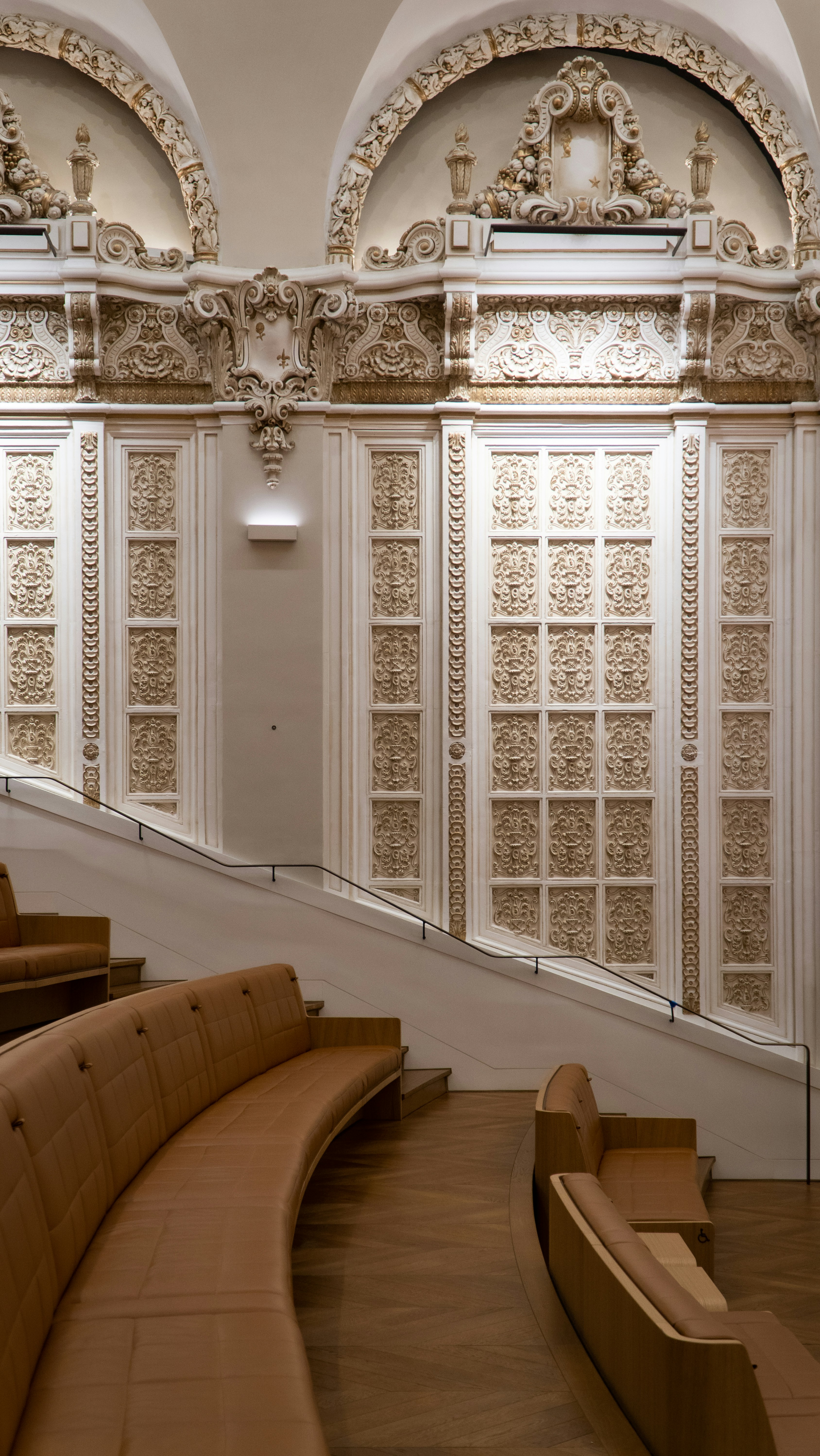 eine geschwungene Holzbank vor einem Fenster