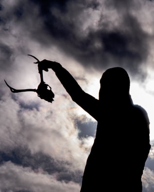 A proud hunter holding a trophy whitetail deer against the backdrop of Texas plains at sunset.