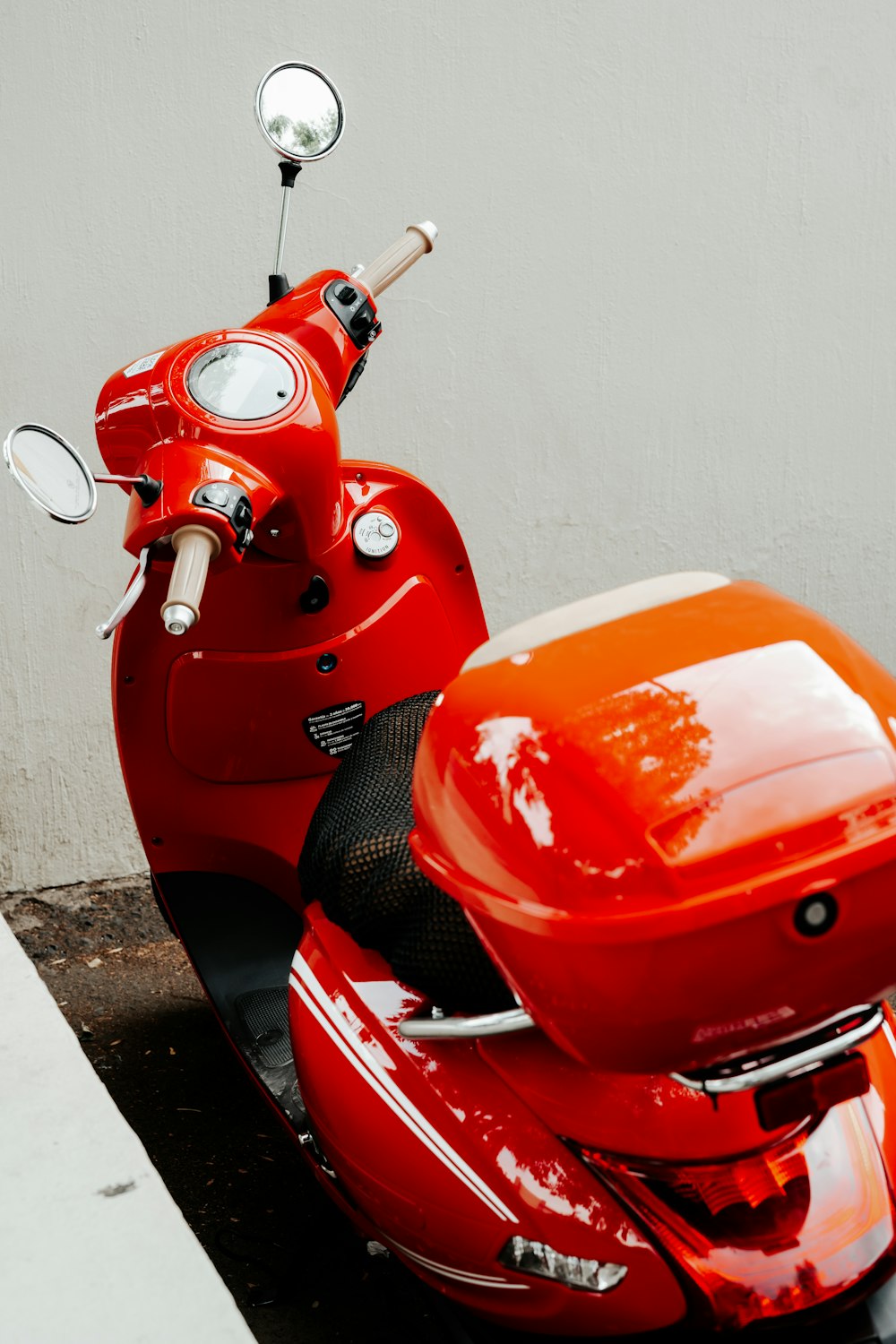 a red scooter parked next to a white wall