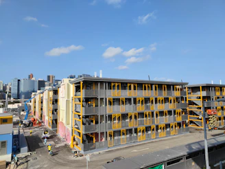 A panoramic view of a modern construction site in Bahrain with Mazari Group workers actively building a large commercial structure.