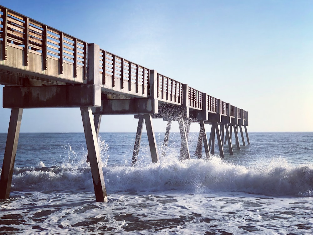 a wooden pier with waves crashing in front of it