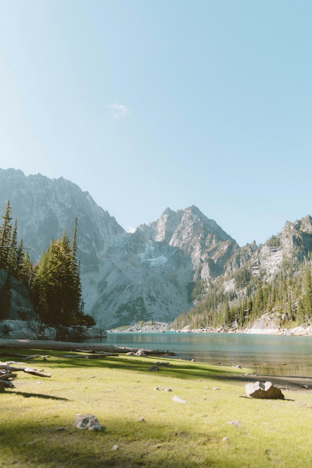 a grassy field next to a lake with mountains in the background