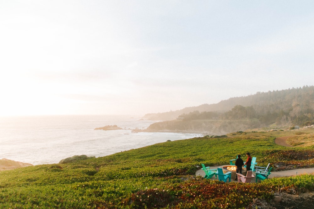 a couple of people sitting at a table on top of a lush green hillside