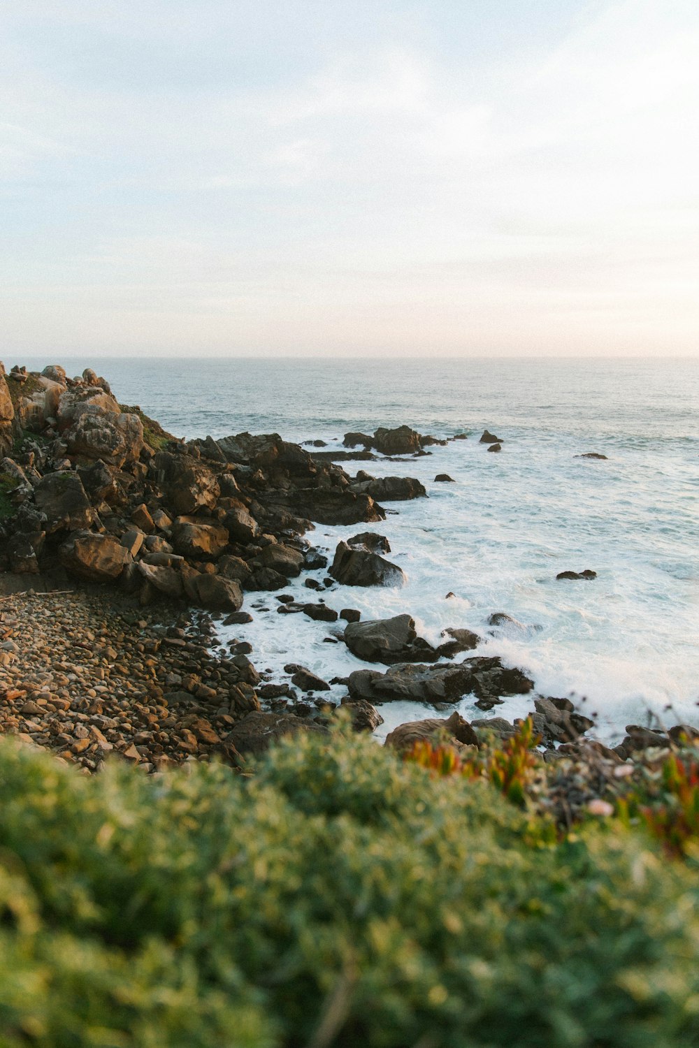 a couple of people sitting on a bench next to the ocean