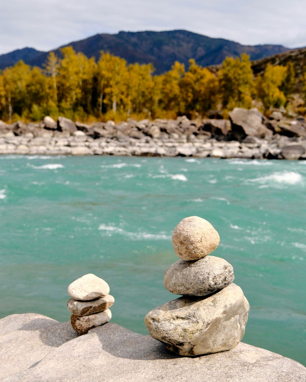 a pile of rocks sitting on top of a rock next to a river