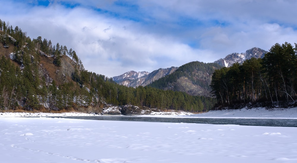 Ein Fluss, umgeben von schneebedeckten Bergen unter einem bewölkten Himmel