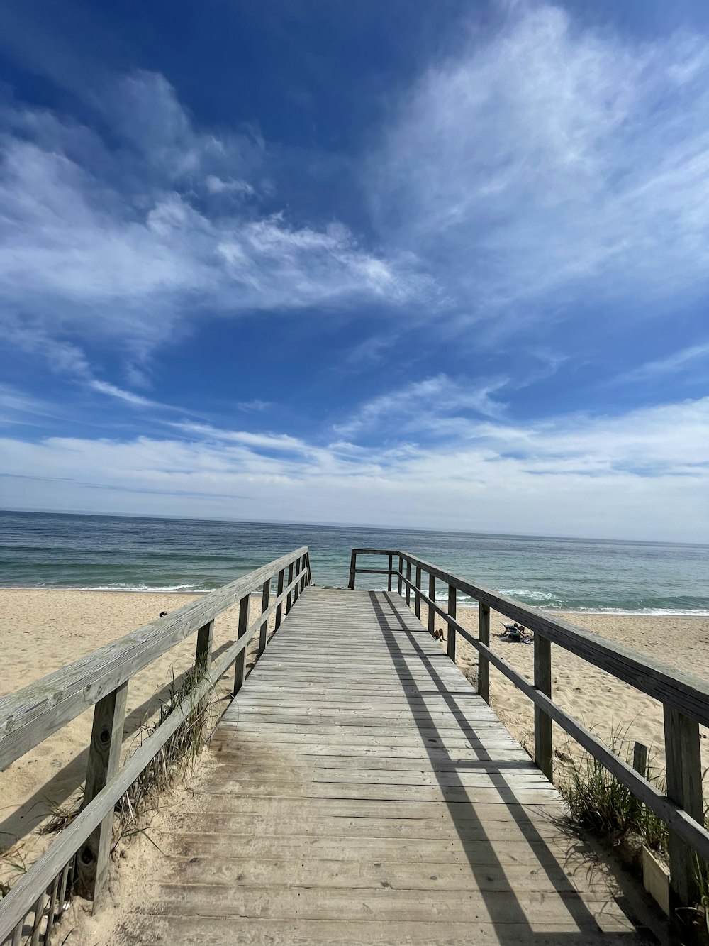 a wooden walkway leading to the beach on a sunny day