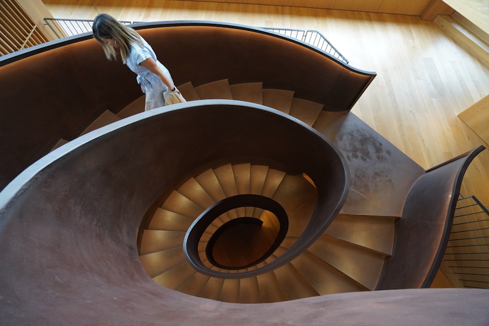 a woman walking up a spiral staircase in a building