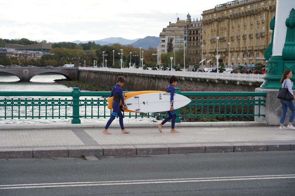 a couple of people walking down a street with a surfboard
