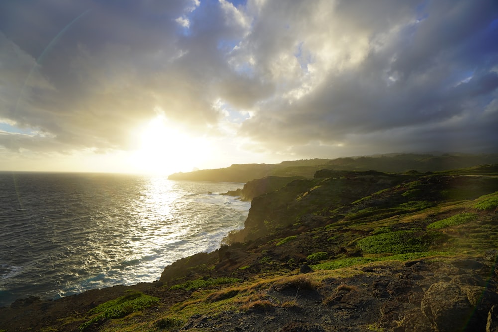 the sun is setting over the ocean on a cloudy day