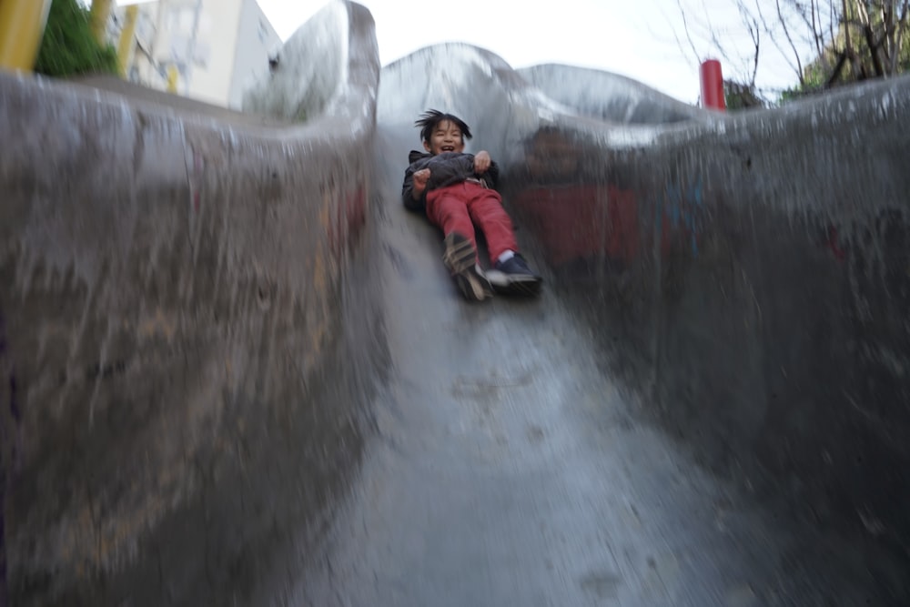 a young boy is sliding down a ramp on a skateboard