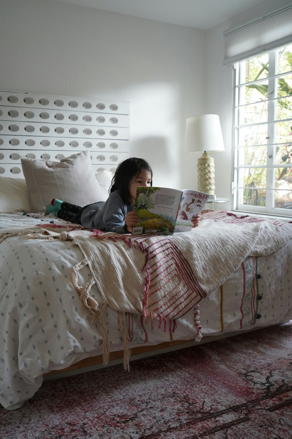 a girl laying on a bed reading a book