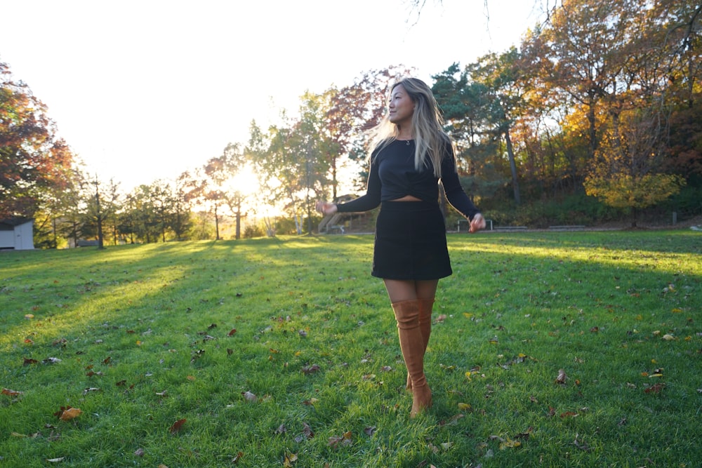 a woman in a black dress is standing in the grass
