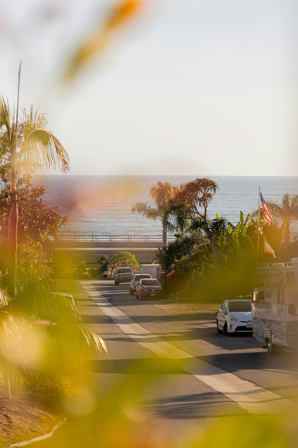 a view of a street with cars and a beach in the background