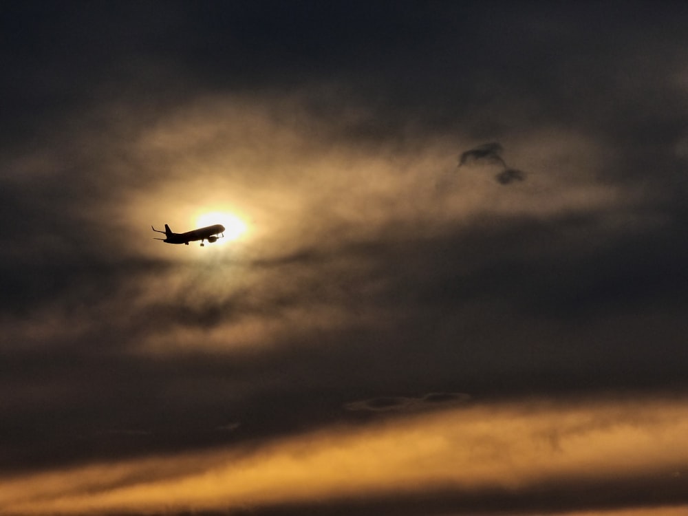 a plane flying in the sky with the sun in the background