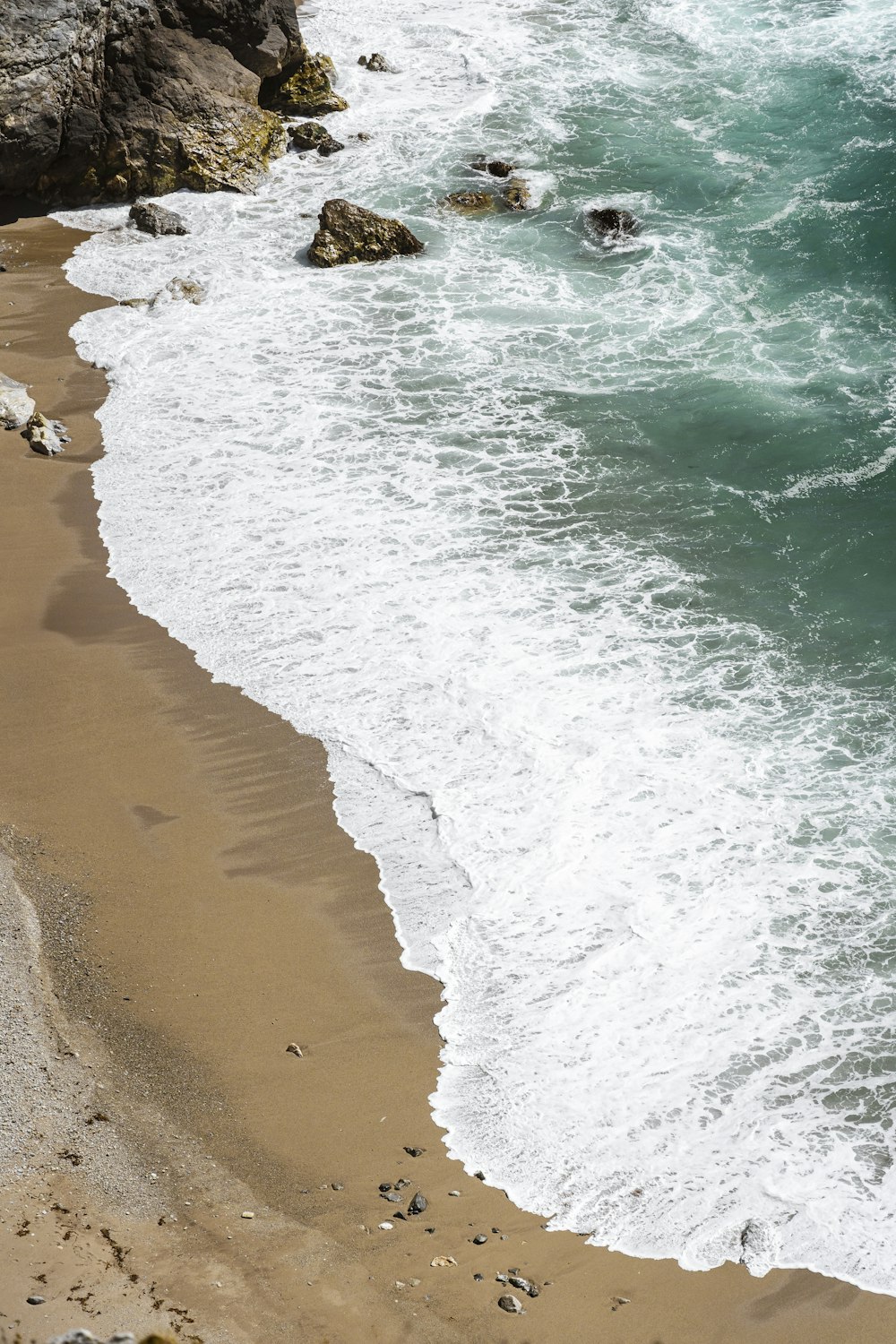 una persona che cavalca una tavola da surf su una spiaggia coperta di onde