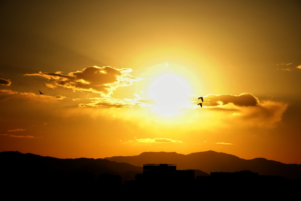 the sun is setting over a city with mountains in the background