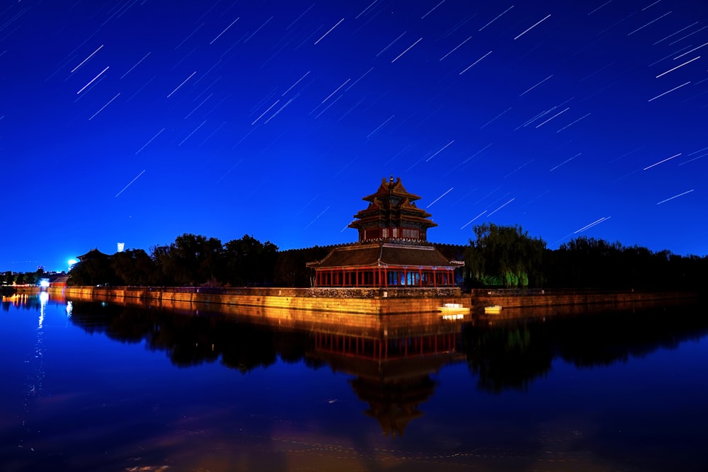 a building sitting on top of a lake under a night sky