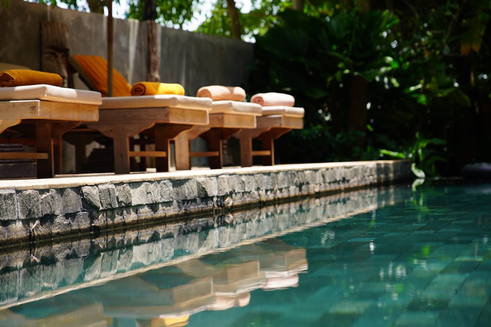 a row of wooden chairs sitting next to a pool