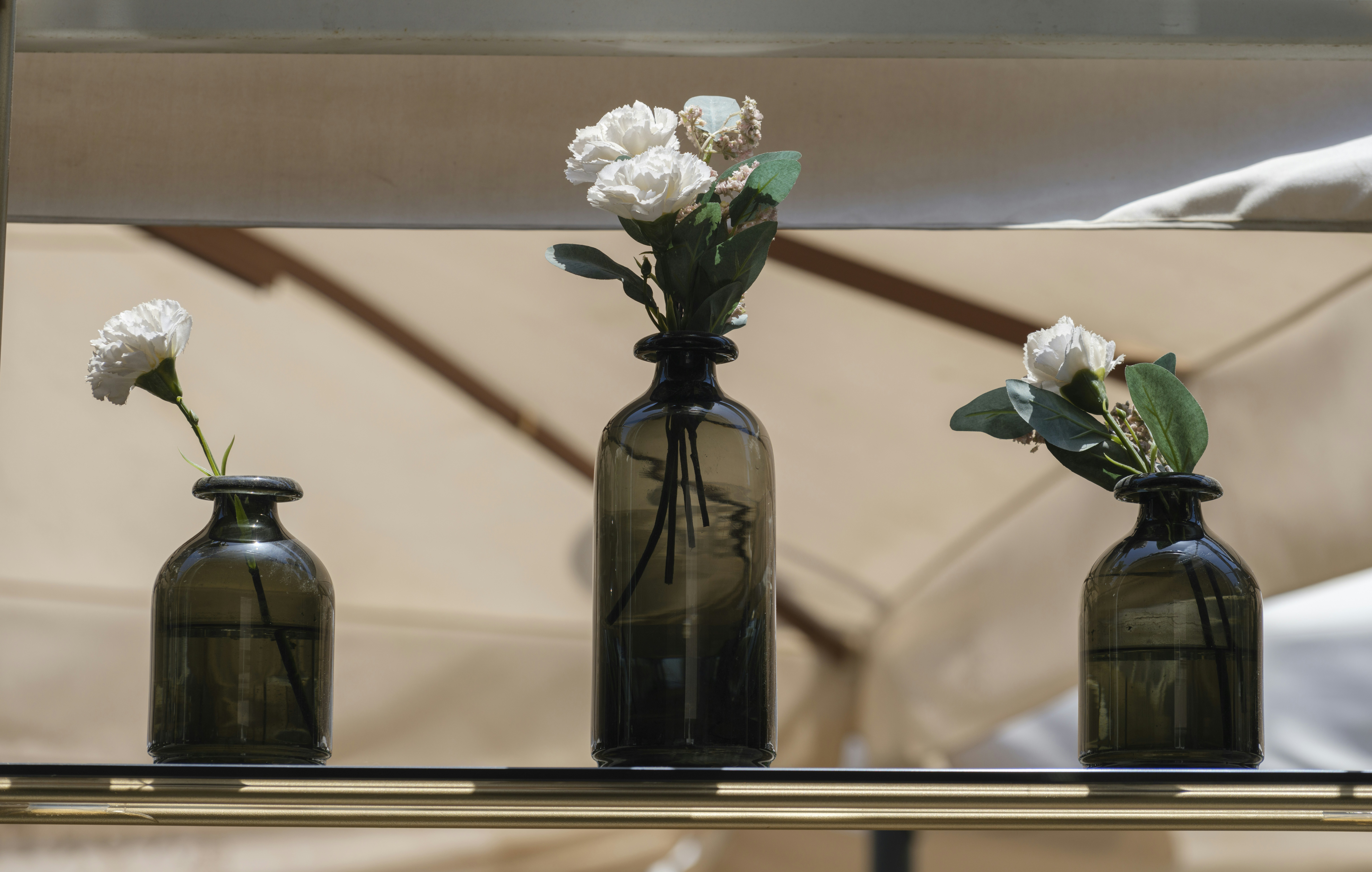 three vases with flowers are sitting on a shelf