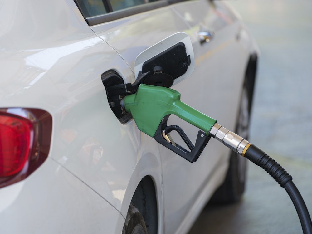 a white car with a green gas pump