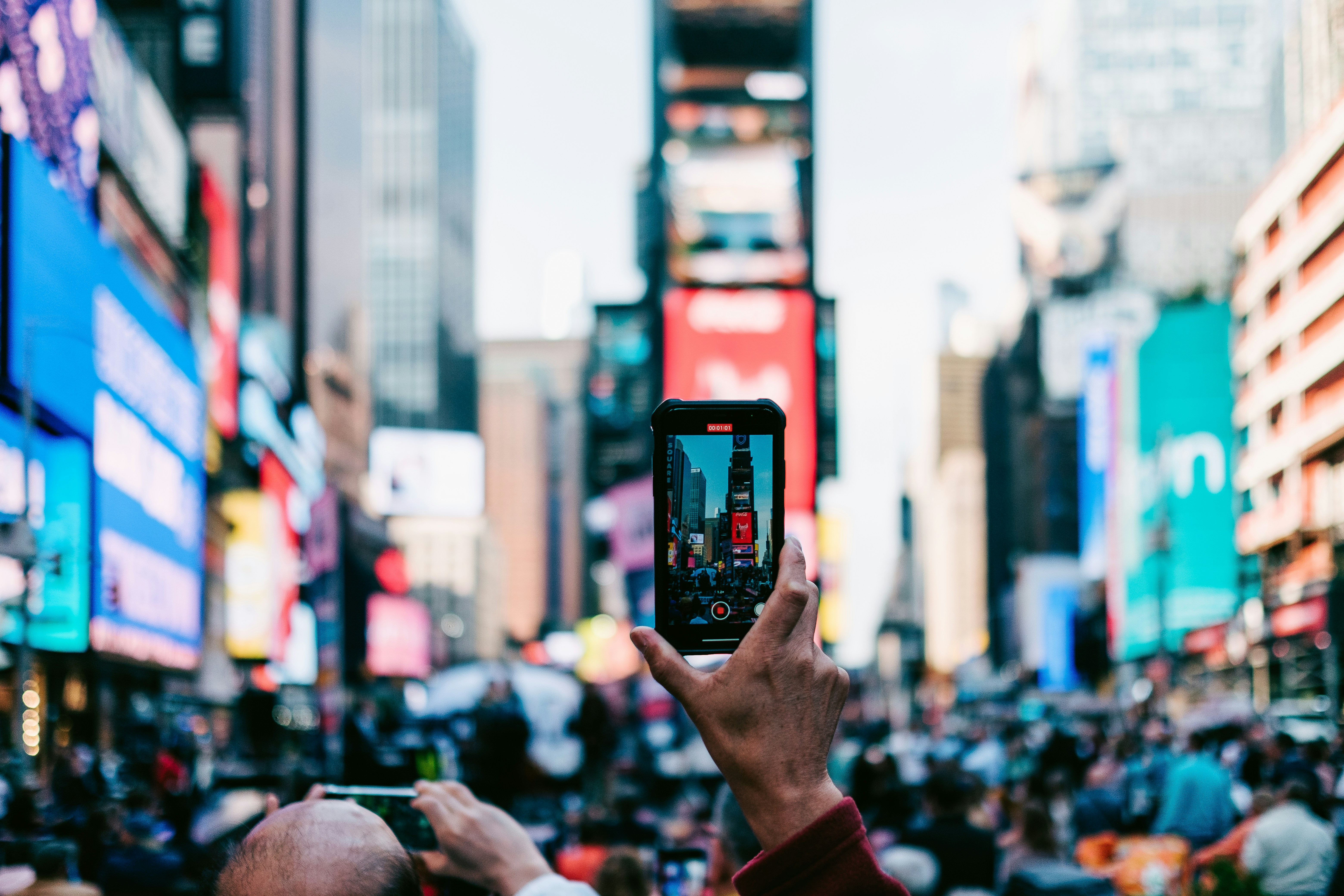 A person using a smartphone on a busy city street in the USA