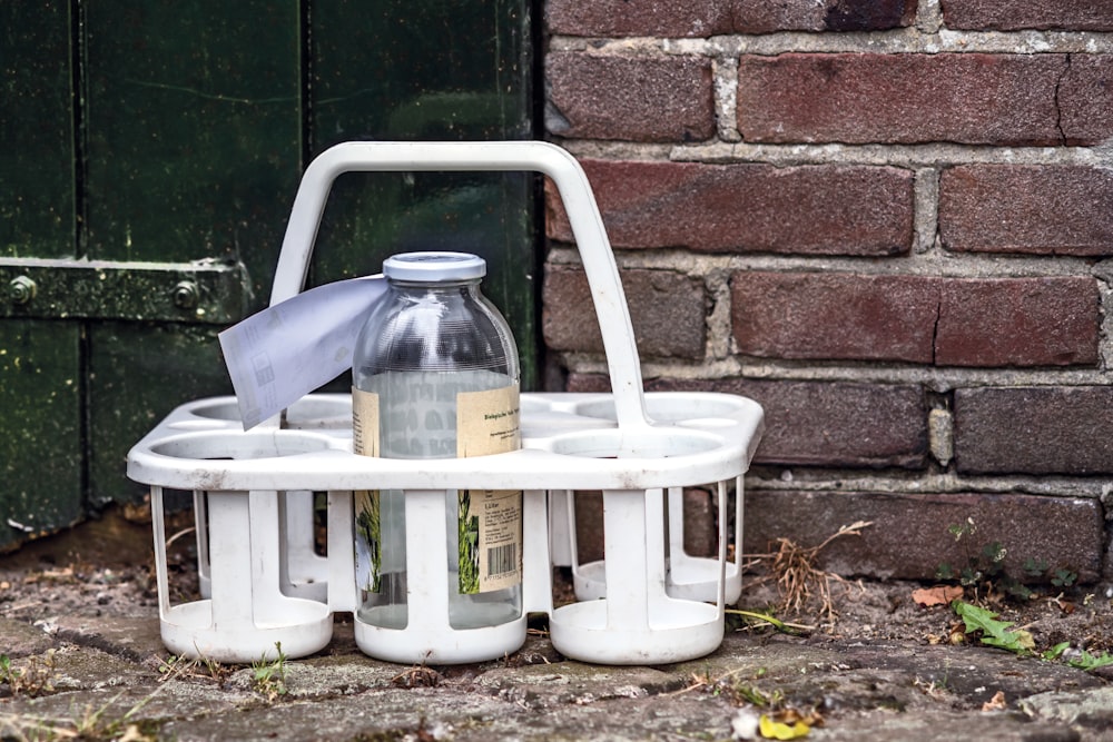 a white basket with a bottle on top of it