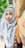 a woman wearing a head scarf standing next to a tree