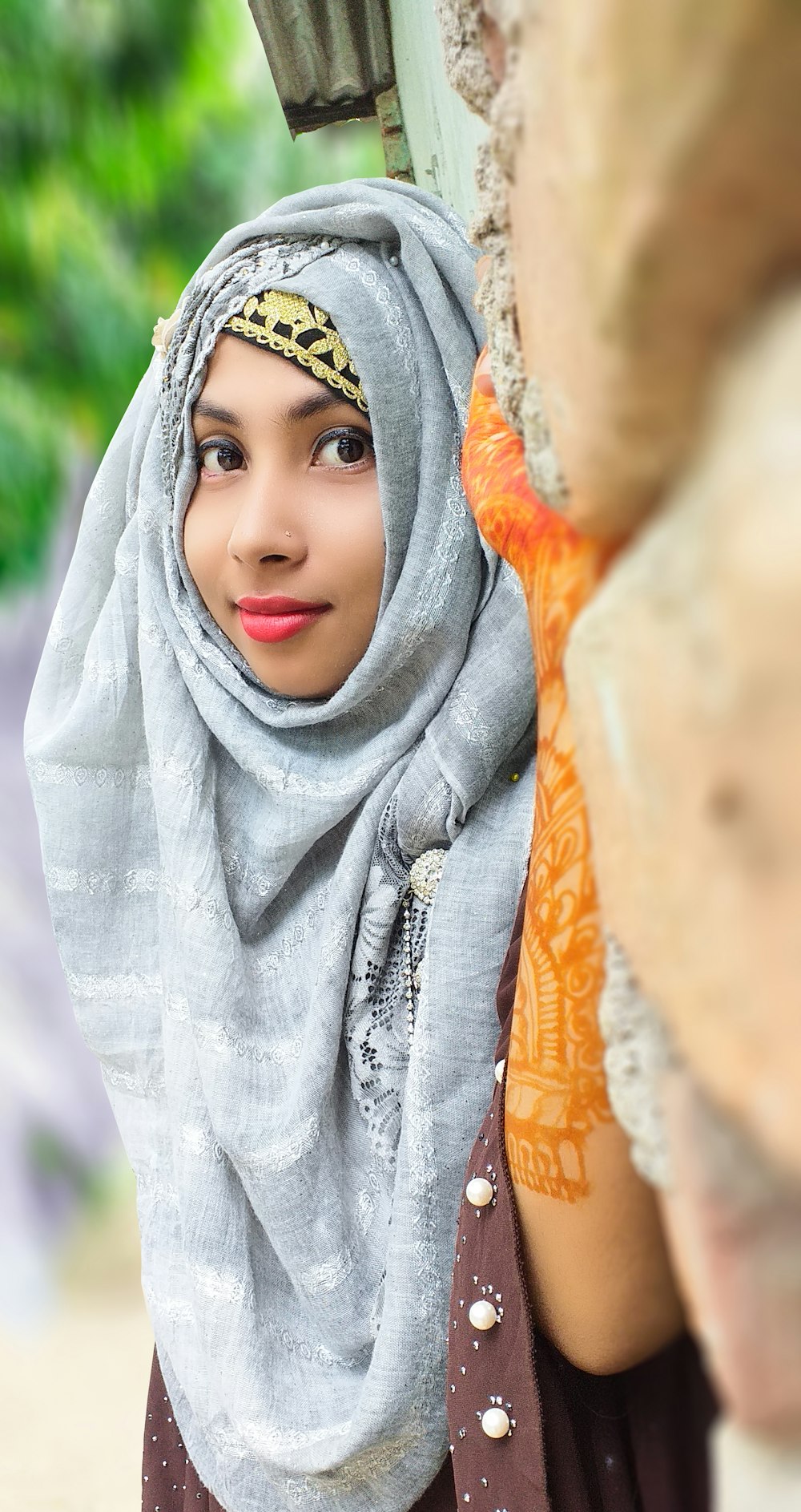 a woman wearing a head scarf standing next to a tree