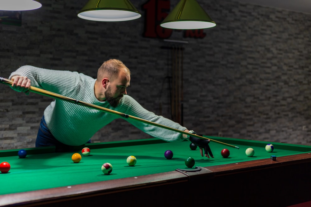 a man leaning over a pool table with a cue in his hand