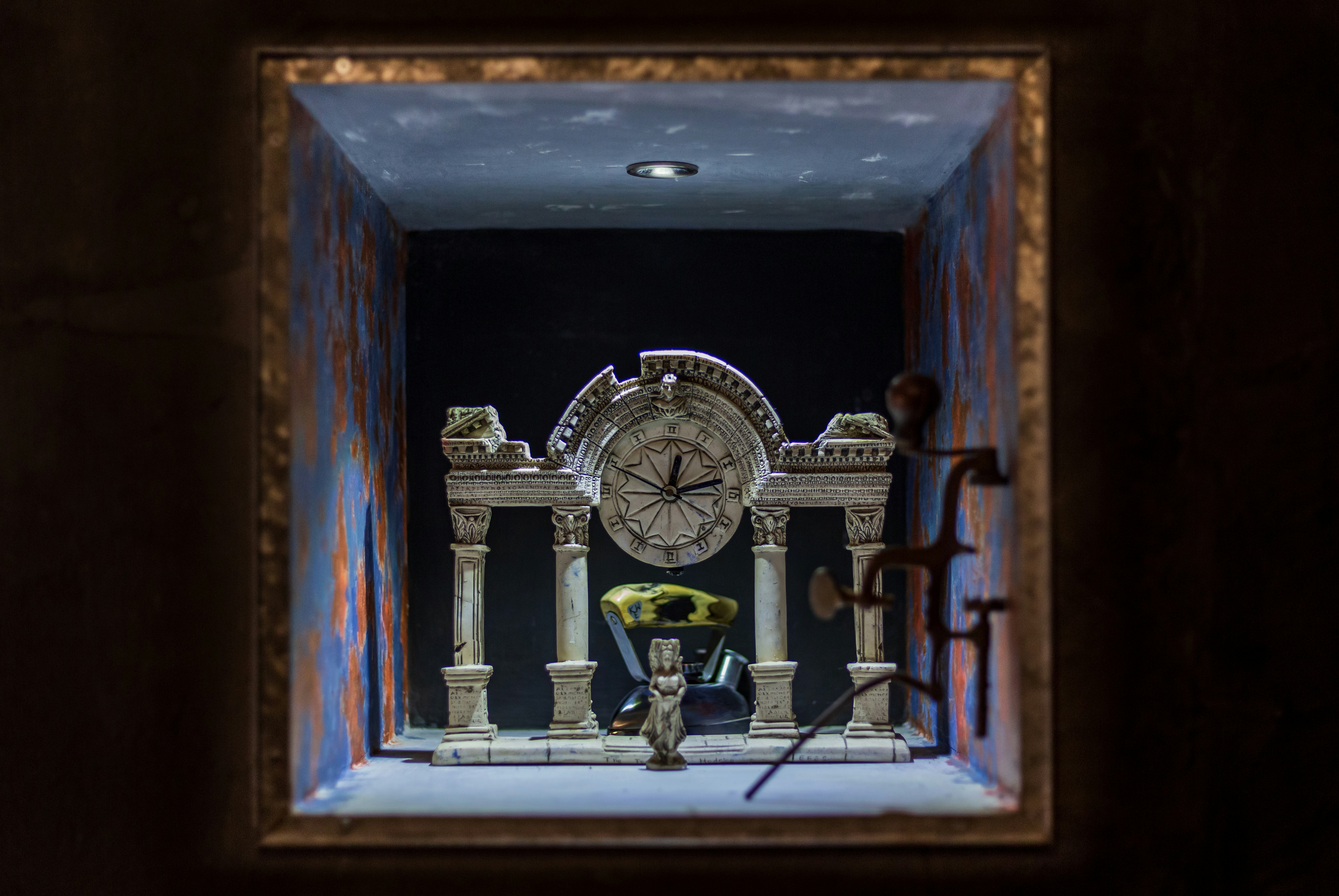 a clock in a room with a man sitting on a chair
